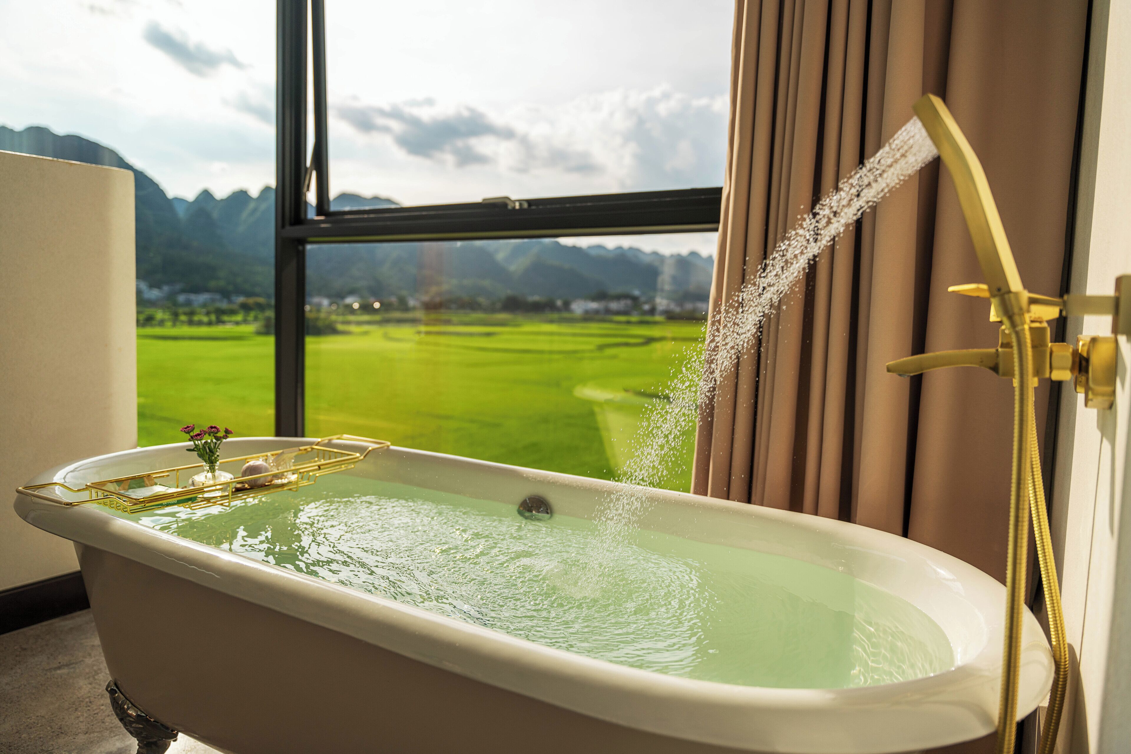Une baignoire donnant sur un paysage verdoyant, visible à travers une fenêtre.
