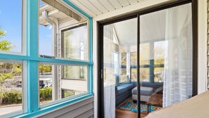A room with a sliding glass door leading to an outdoor seating area with a bench and cushions.