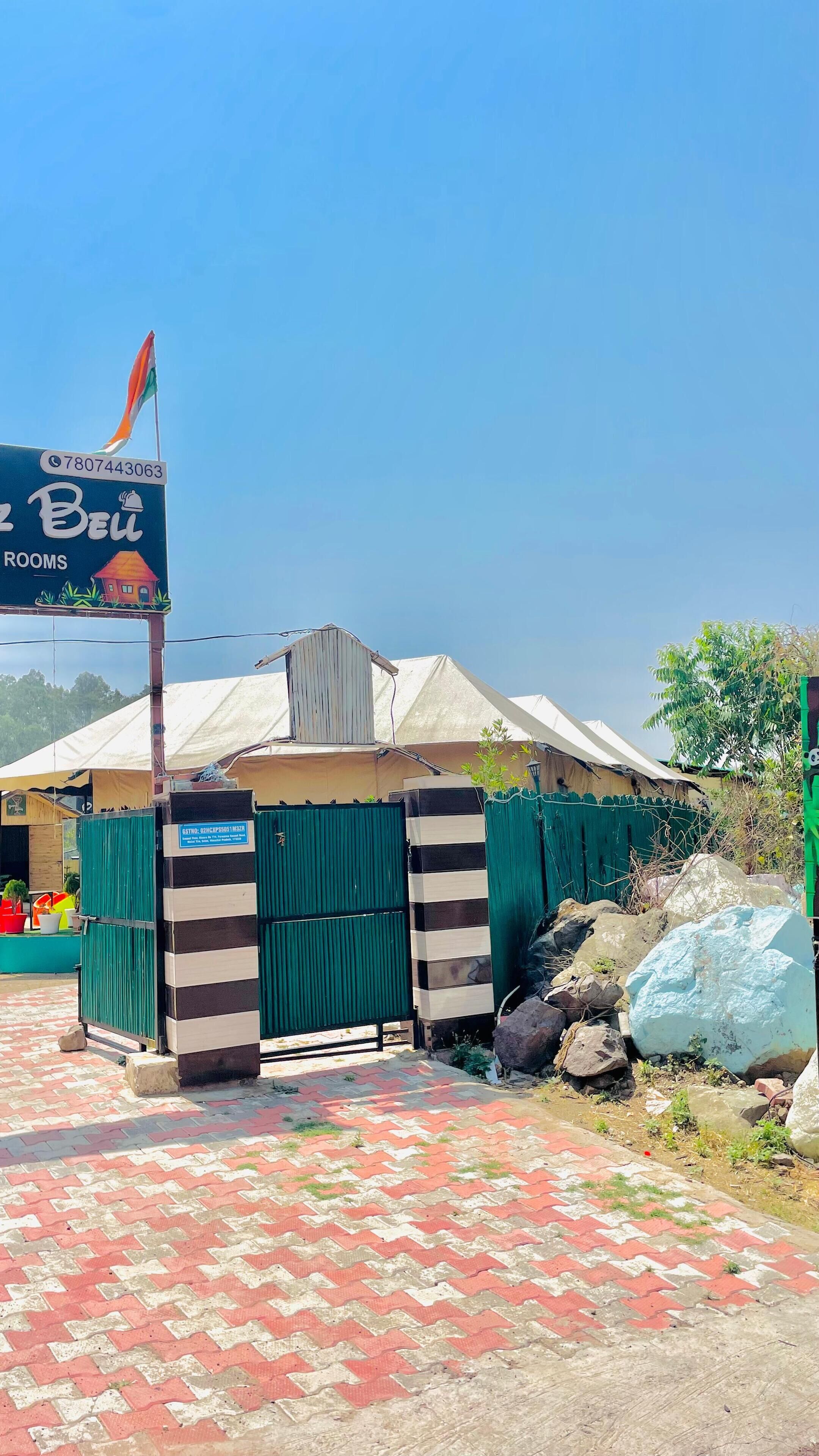 A hotel entrance with a signboard, a flag, and a gated entrance.