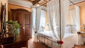Une chambre à coucher avec un lit à baldaquin, une commode en bois et une table de chevet avec une lampe.