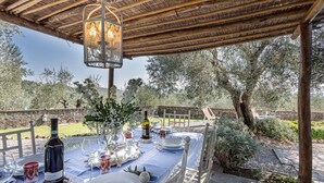Un espace de restauration en plein air avec une table dressée pour deux personnes, sous une pergola en bois illuminée par une lanterne.