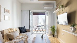 A modern living room with a sofa, coffee table, and a balcony with a view of the city. - Santorini-2-Bedroom Apt in Nea Smyrni (Nea Smirni)