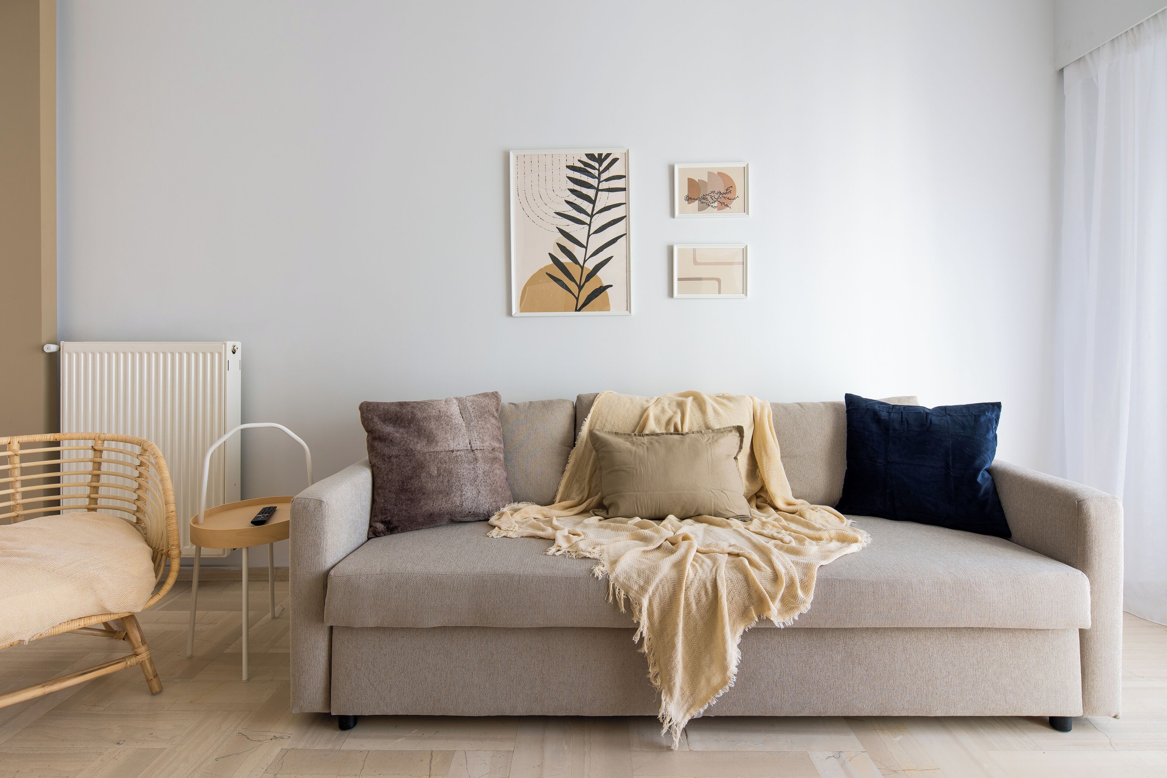 Un salon comprenant un canapé, un fauteuil et deux œuvres d’art accrochées au mur.