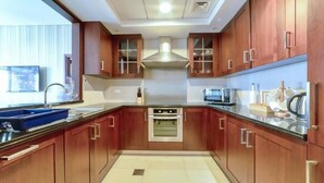 A modern kitchen with wooden cabinets, stainless steel appliances, and a large window.