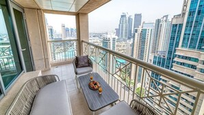 A balcony with a view of a cityscape, a table with a plate of food, and a sofa.