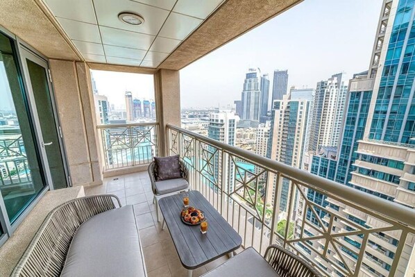 A balcony with a view of a cityscape, a table with a plate of food, and a sofa.