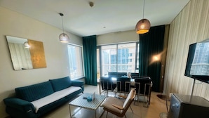 A modern living room with a sofa, coffee table, TV, and dining area.