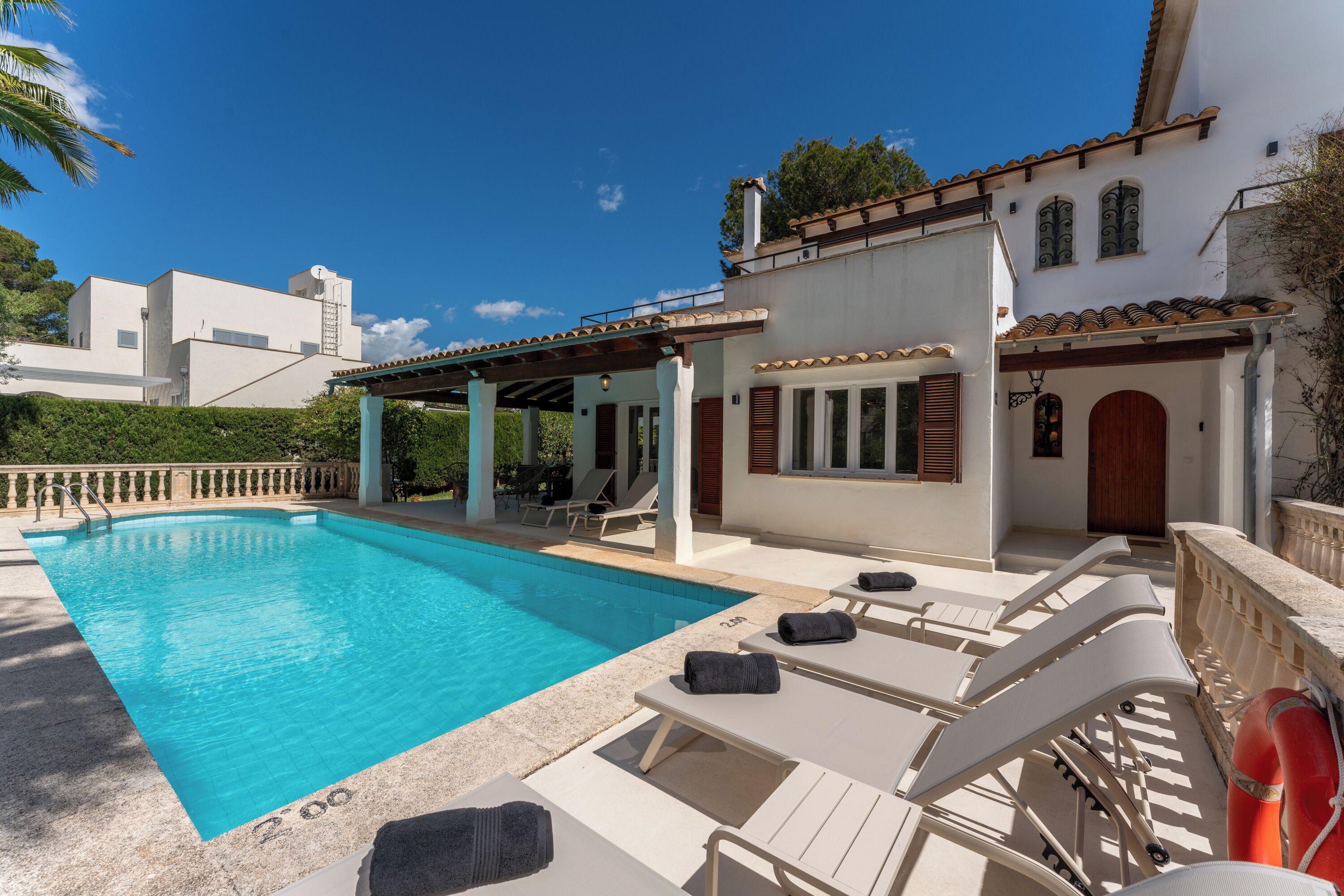 A swimming pool with lounge chairs and a covered patio area.