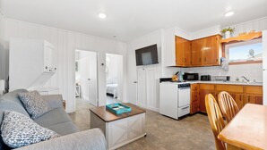 A modern kitchen with white cabinets, a built-in oven, and a flat-screen TV. - Charming 2-Bedroom Getaway A/C, WIFI, Covered porch just 3 Minutes to the Beach! (Hampton)