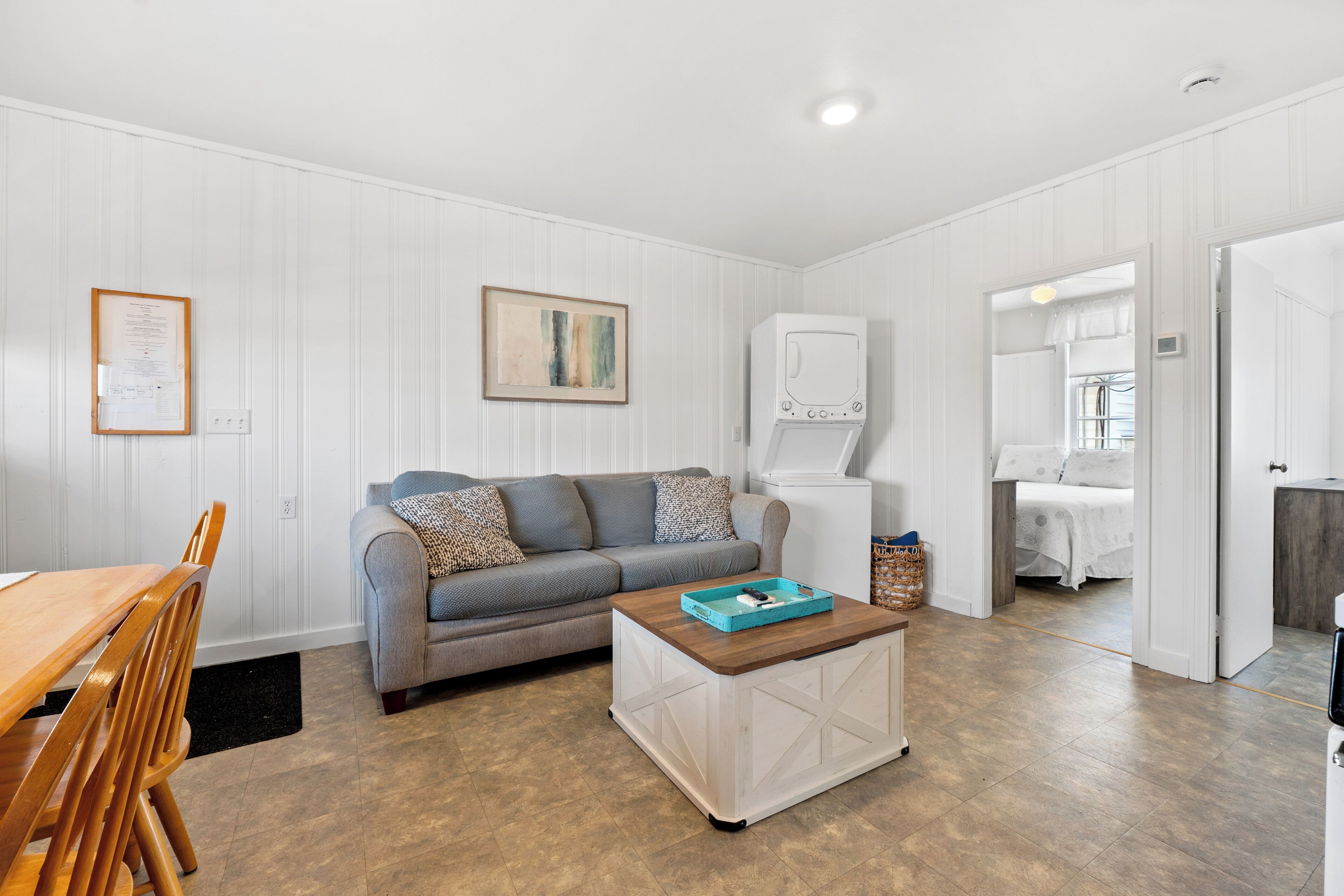 A living room with a sofa, coffee table, and a white refrigerator.