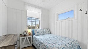 A bedroom with a bed, a window, a bedside table, and a nightstand. - Charming 2-Bedroom Getaway A/C, WIFI, Covered porch just 3 Minutes to the Beach! (Hampton)