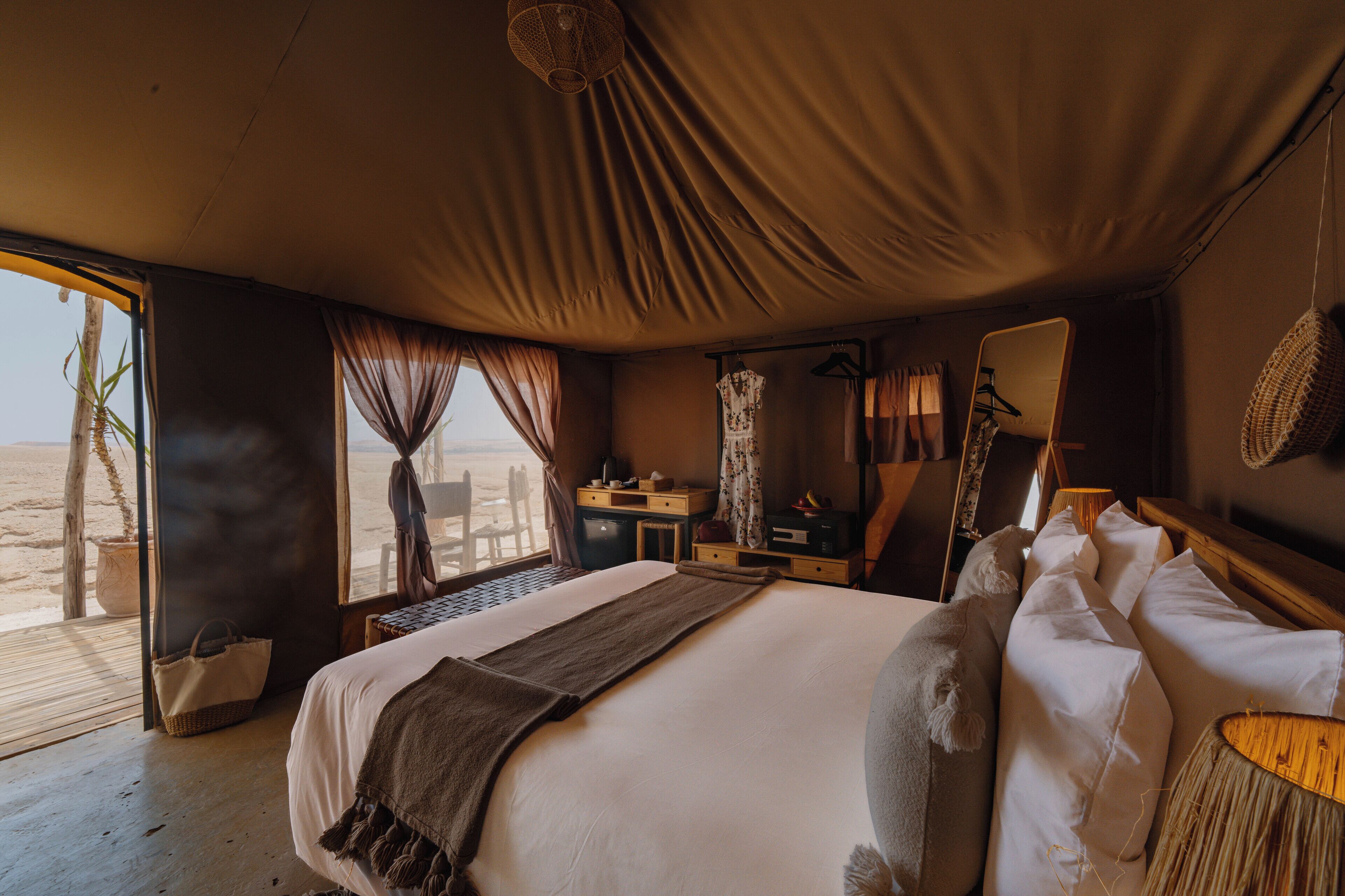 Une chambre avec un grand lit, un bureau, une chaise, un miroir et une vue sur la plage.