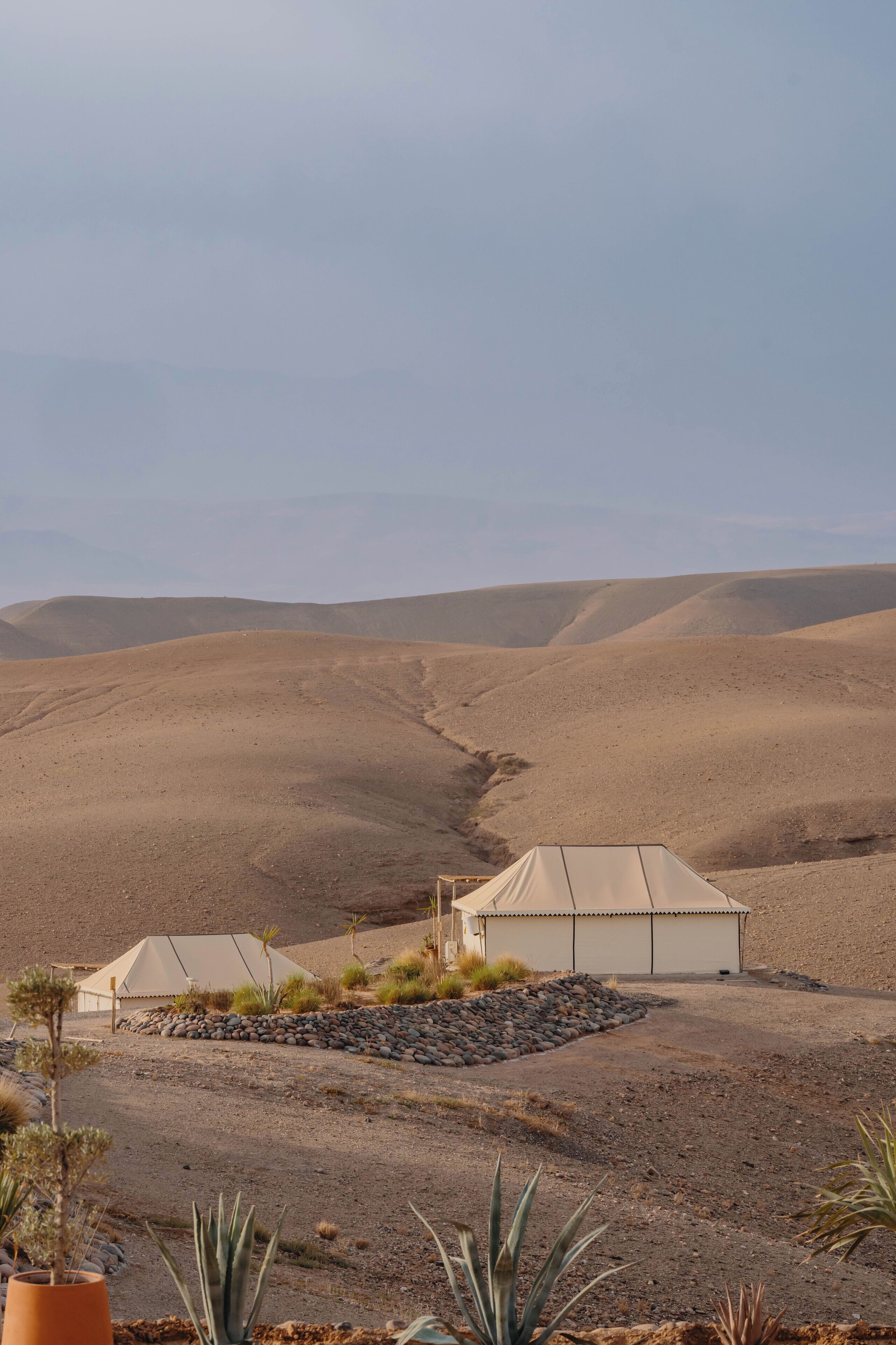 A desert landscape with tents and sparse vegetation.