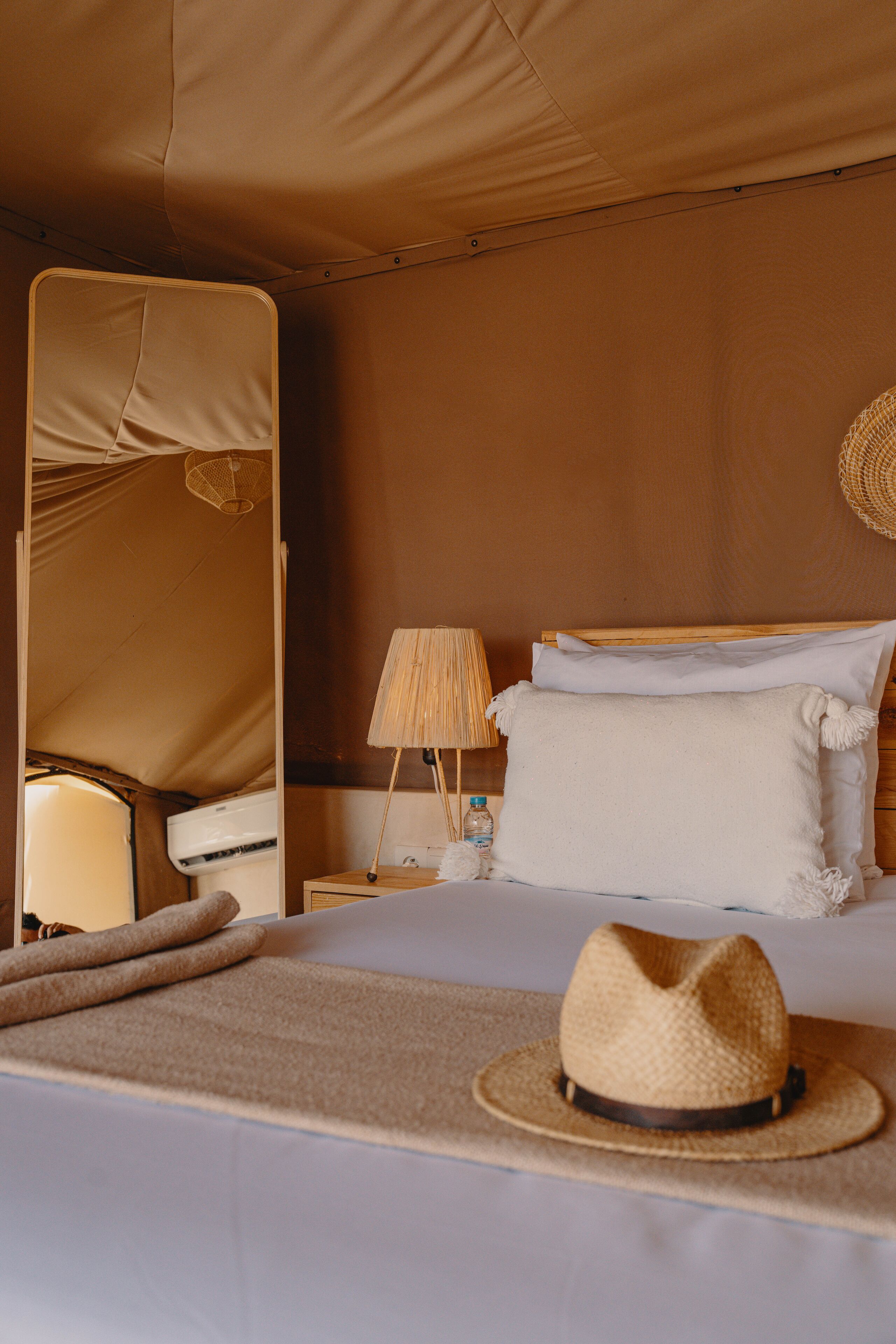 A bed with a straw hat, a lamp, and a canopy.