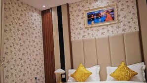Une chambre d’hôtel avec un grand lit, une tête de lit, un téléviseur fixé au mur et une petite table.