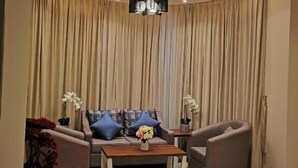Un salon moderne doté d’un plafond incurvé, d’un ensemble de canapés, de deux fauteuils, d’une table basse et d’un lustre.