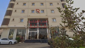 A multi-story hotel with a prominent 'R' logo, a glass entrance, and a car parked in front. - Sama Al Riffa Serviced Apartments (Al Kharj)