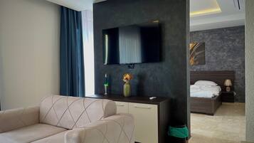 Luxe suite, gedeeltelijk uitzicht op zee | Woonruimte | Een 70-inch smart-tv met digitale zenders