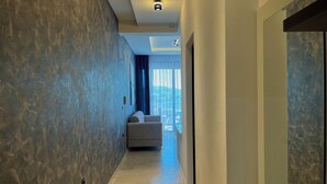 Un couloir moderne avec un mur texturé, un canapé et une vue sur un balcon.