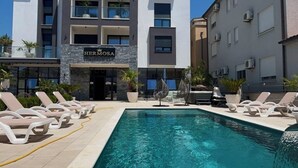 Un hôtel moderne doté d’une piscine, de chaises longues et d’une enseigne indiquant le nom « Hermosa ».