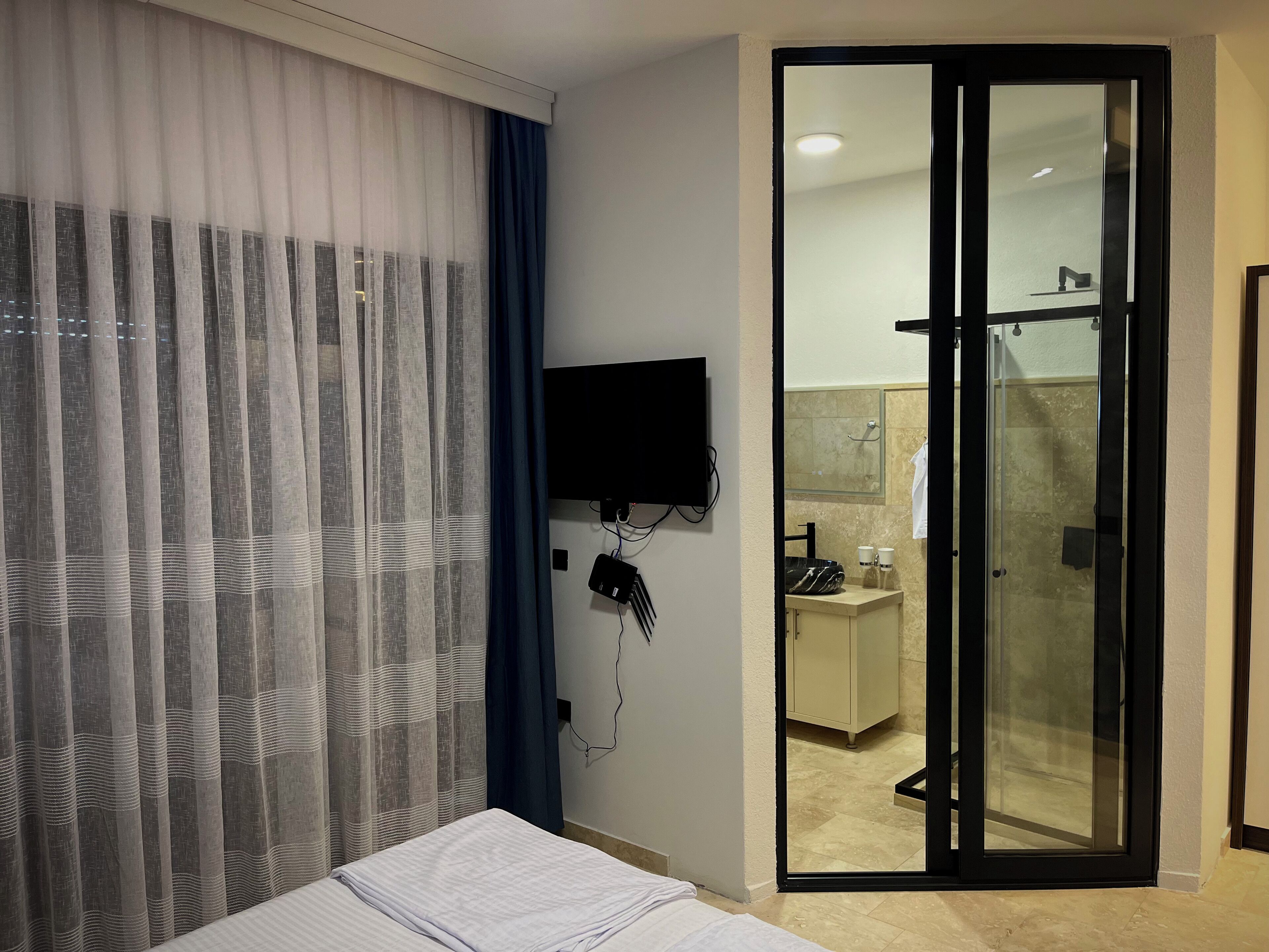 A hotel room with a bed, a TV mounted on the wall, and a sliding door leading to a bathroom.