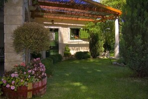 Une maison avec un jardin, une pergola et un petit arbre.