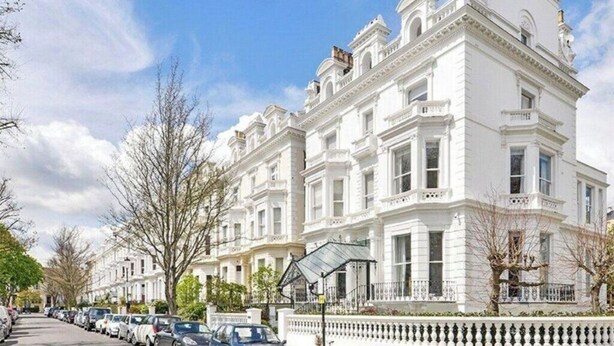 A row of white Victorian-style townhouses with a uniform facade, parked cars along the street, and a clear blue sky. - Charming Notting Hill Mews House (London)