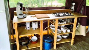 Eine kleine Küche mit einem Gaskochfeld, einer Kaffeemaschine und diversen Küchengeräten.
