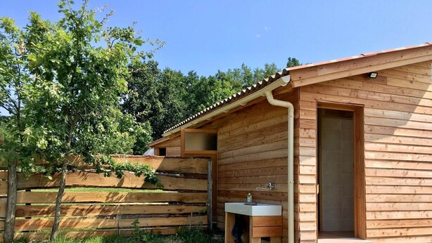 Eine Holzhütte mit einem kleinen Badezimmer, einem Waschbecken und einer Tür.