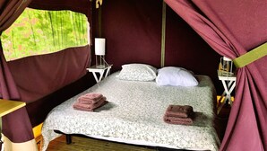 Ein Einzelbett mit floralem Überwurf, zwei Kissen und zwei gefaltete Handtücher.