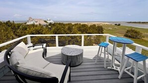 Terraza con sofá, dos sillones y una mesa, con vistas a la playa y al océano.