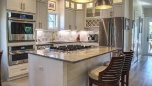 Una cocina moderna con electrodomésticos de acero inoxidable, una isla grande y taburetes de bar.