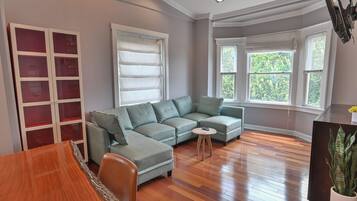 Una sala de estar con un sofá modular, una mesa de comedor y un aparador con puertas de vidrio.