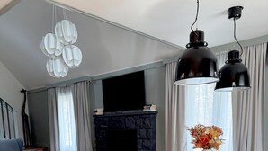 Een moderne woonkamer met een open haard, een eettafel met stoelen en een rode bank.
