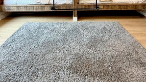 Een slaapkamer in loftstijl met een houten plafond en zichtbare balken, met twee stapelbedden voorzien van witte beddengoed en oranje sierkussens.
