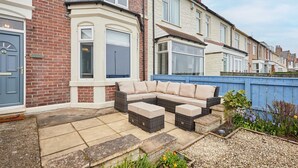 A residential property with a large patio area, a built-in sofa, and a small garden. - Host Stay Twelve On The Terrace (Newbiggin-by-the-Sea)