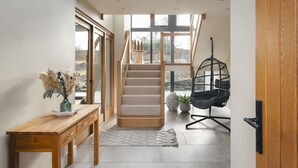 A modern interior with a wooden desk, a staircase, and a hanging chair. - Lily Bank in Staveley (Kendal)