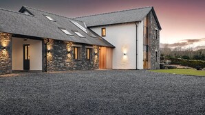 A modern house with a stone facade, a sloped roof, and a gravel driveway. - Lily Bank in Staveley (Kendal)