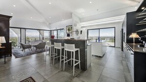 Una cocina amplia con una isla central, ventanas grandes y un techo alto.