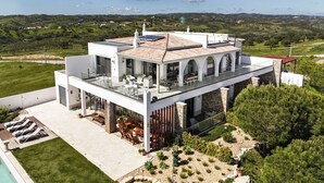 Una casa moderna de dos pisos con techo plano, ventanas grandes y una piscina.