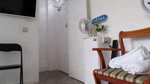 A compact room with a bed, a chair, a small table with a fan, and a sign reading "HABANA". - Apartmentsleeps4-west Kensington-petsok-parking (London)