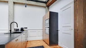 A modern kitchen with a central island, built-in appliances, and a wooden floor. - A PERFECT BLEND OF CLASSIC ELEGANCE & MODERN COMFORT NEXT TO LUXEMBOURG GARDEN (Paris)