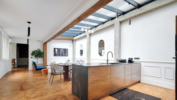 A modern kitchen with a large island, wooden flooring, and a skylight. - A PERFECT BLEND OF CLASSIC ELEGANCE & MODERN COMFORT NEXT TO LUXEMBOURG GARDEN (Paris)
