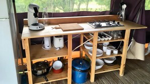 Un espace cuisine compact comprenant une cuisinière à gaz, une machine à café et divers ustensiles de cuisine.