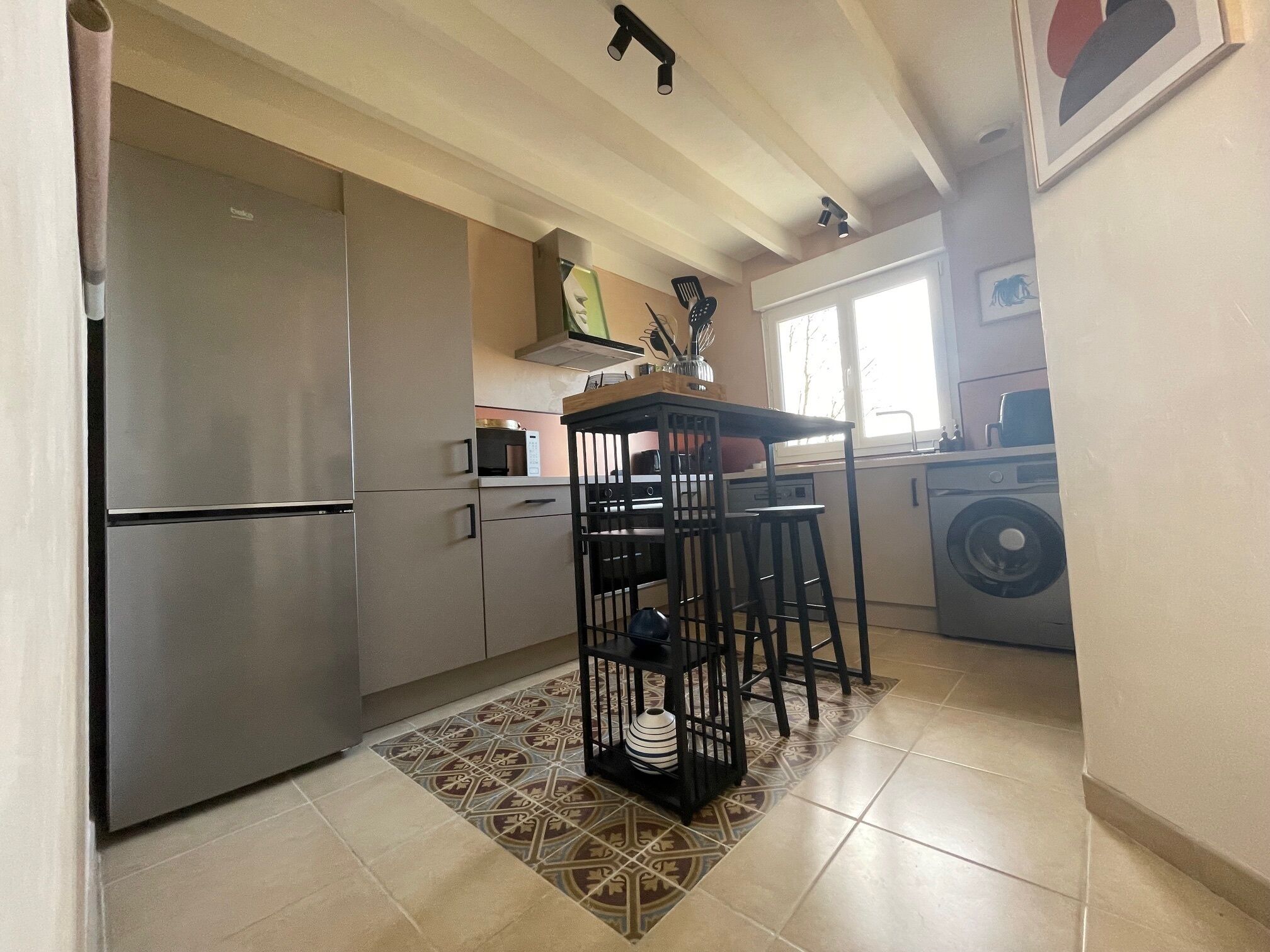 Una cocina compacta con refrigerador integrado, microondas y lavadora.