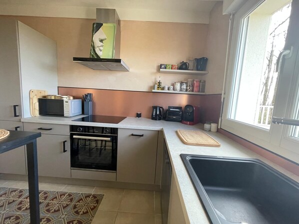 Una cocina compacta con estufa, microondas y fregadero.