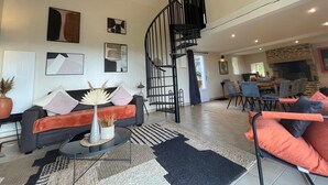 A spacious living area with a modern sofa set, a coffee table, and a black spiral staircase.