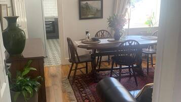 A dining area with a wooden table and chairs, a patterned rug, and a large green vase.