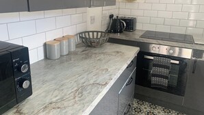 Une cuisine avec un dosseret de carrelage blanc, une machine à café noire, un grille-pain et un four en acier inoxydable.