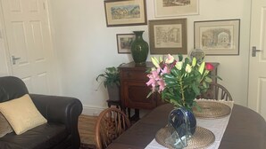 Un coin repas avec une table en bois, un vase de fleurs et des œuvres d’art encadrées accrochées au mur.